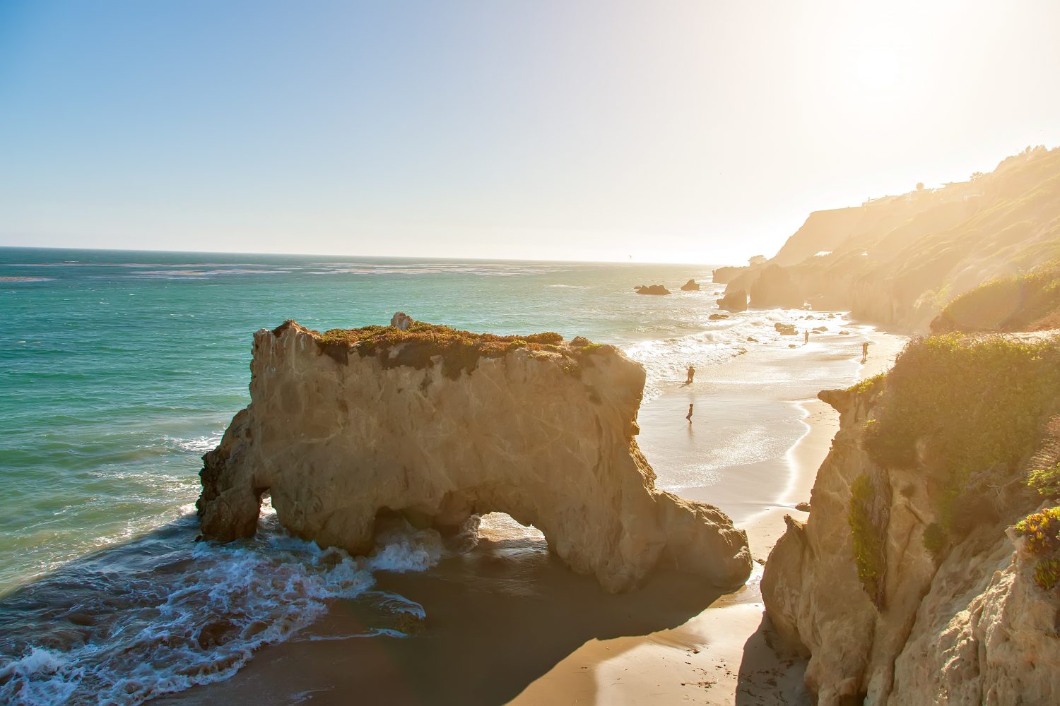 Sunlight over the sea arch and surf at El Matador Beach on the Southern California coast