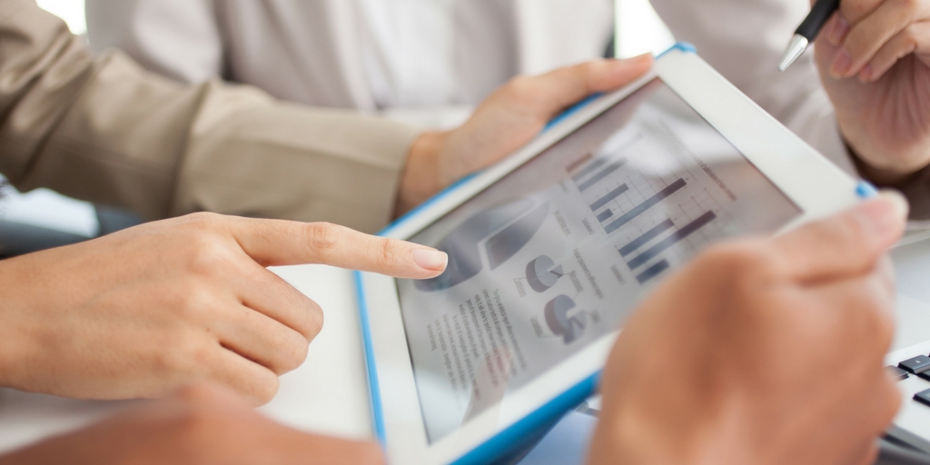 An advisor and a client review portfolio charts on a tablet across a desk